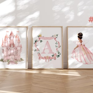 Puede incluir: Tres impresiones en acuarela enmarcadas. La primera representa un castillo rosa. La segunda presenta la letra "A" dentro de una corona floral. La tercera muestra un hada con un vestido rosa. Las impresiones se exhiben en un suelo de madera.