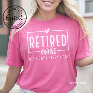 May include: Pink t-shirt with white text that reads "RETIRED mode ALL DAY EVERY DAY" and a small heart above the word "RETIRED".
