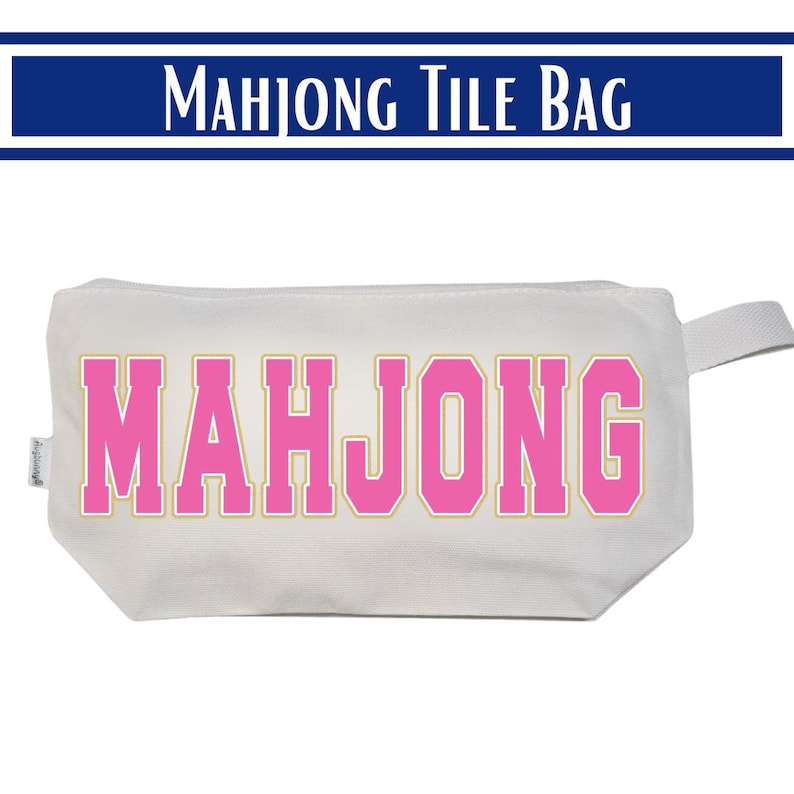 May include: A white rectangular fabric pouch featuring the word MAHJONG printed in large pink block letters with a thin gold outline. The bag has a small side tab and a zipper closure, designed for storing game tiles or other small items.