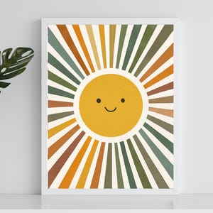 May include: A digital print of a smiling sun with yellow rays in shades of orange, brown, and green. The sun is surrounded by a white frame.