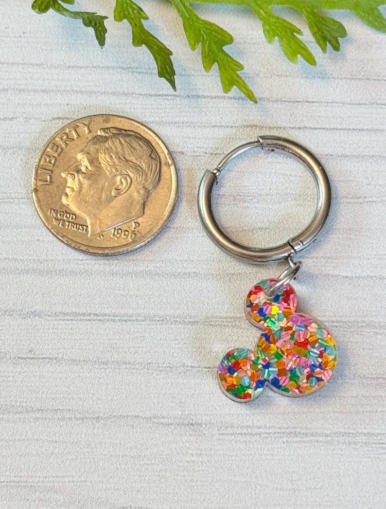 May include: A silver hoop earring with a colourful confetti Mickey Mouse charm. The charm is about the size of a ten pence piece.
