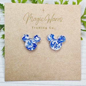 May include: A pair of blue and white patterned Mickey Mouse earrings. The earrings are made of resin and have a glossy finish.