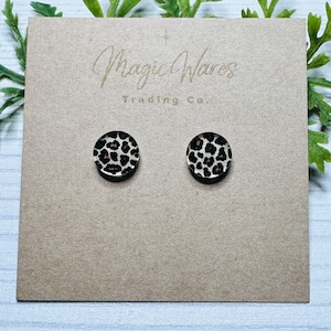May include: A pair of small, round, leopard print earrings on a brown card with the text "Magic Wares Trading Co."