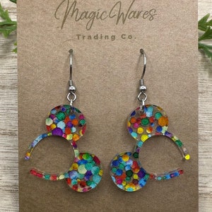 May include: A pair of colorful confetti Mickey Mouse ear-shaped dangle earrings with silver hooks. The earrings are made of clear acrylic with a confetti pattern.