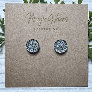 May include: A pair of round, black and white geometric patterned earrings on a brown card with the text "Magic Wares Trading Co."