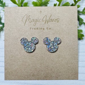 May include: A pair of silver glitter Mickey Mouse earrings on a brown card with the text "Magic Wares Trading Co."