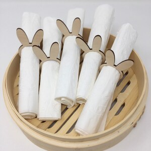 Puede incluir: Un juego de seis servilletas blancas con anillos de servilleta de madera con forma de conejo. Los anillos son de madera natural y tienen un dise&ntilde;o de conejo simple. Las servilletas y los anillos est&aacute;n en un vaporizador de bamb&uacute; redondo.