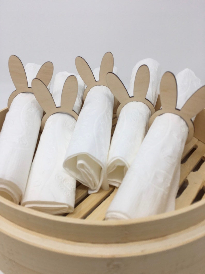 Puede incluir: Un juego de seis anillos de servilleta de madera con forma de conejo en una vaporera de bamb&uacute;. Los anillos est&aacute;n hechos de madera natural y tienen un dise&ntilde;o simple y elegante. Son perfectos para a&ntilde;adir un toque de fantas&iacute;a a la decoraci&oacute;n de tu mesa.