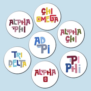 May include: Seven white circular stickers with colorful text, including "ALPHA PHI", "CHI OMEGA", "ALPHA CHI", "AD Pi", "TRI DELTA", "ALPHA O", and "PHI". The text is in various colors, such as red, blue, green, and yellow.