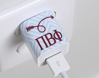 May include: A white phone charger with a blue and white chevron pattern and a maroon arrow design. The charger has the letters "ПВФ" printed on it.