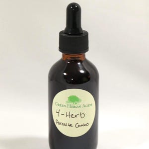 以下が含まれることがあります： 黒いスポイトキャップが付いた濃い琥珀色のガラス瓶。ボトルには「Green Heron Acres 4-Herb Parasite Combo」と書かれた白いラベルが付いています。中の液体は濃い茶色です。