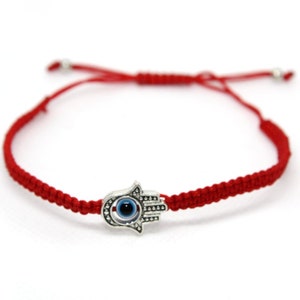 May include: Red string bracelet with a silver charm featuring a hamsa hand with a blue evil eye.