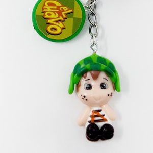 May include: A green and yellow keychain with a cartoon character, a barrel, a sandwich, and a round charm with the text "El Chavo" on it.