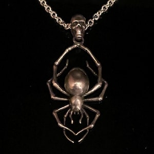 May include: A silver necklace with a skull charm and a detailed spider pendant.
