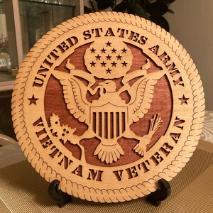 May include: A wooden plaque with a carved United States Army emblem and the text "Vietnam Veteran". The plaque is brown and has a rope-like border.