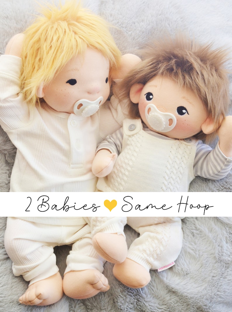 Op de afbeelding: Twee handgemaakte babypoppen van stof met speen, die witte outfits dragen, liggen op een pluche grijs oppervlak. De poppen hebben blond en bruin haar. De tekst "2 Babies &hearts; Same Hoop" is onder de poppen gedrukt.