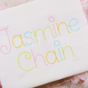 May include: Embroidered name "Jasmine Chan" in a colorful chain stitch font. The letters are outlined in pink, blue, yellow, and green.