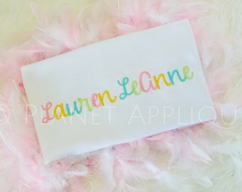 May include: A white onesie with the name "Lauren LeAnne" embroidered in rainbow colors.