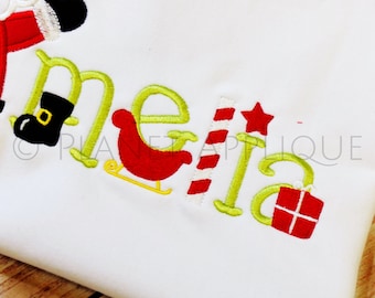 May include: Green embroidered letters spelling "melia" with Christmas-themed embellishments including a Santa boot, a red sleigh, a candy cane, a red star, and a red gift box.