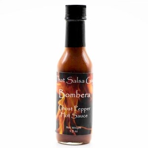 May include: A 5 fl oz bottle of That Salsa Guy Bombiera Ghost Pepper Hot Sauce. The bottle is clear glass with a black cap and a label with a fiery orange and yellow design. The label reads "That Salsa Guy Bombiera Ghost Pepper Hot Sauce".