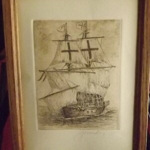 May include: A framed black and white etching of a ship with sails and a cross on each sail. The ship is in the water and the etching is signed "J. Grande" in the bottom right corner.