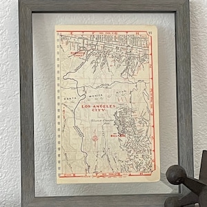 May include: A framed vintage map of Los Angeles, California, showing the city and surrounding areas. The map is printed on cream-colored paper with black and red ink. The map includes the text "Los Angeles City" and "Stone Canyon Res."