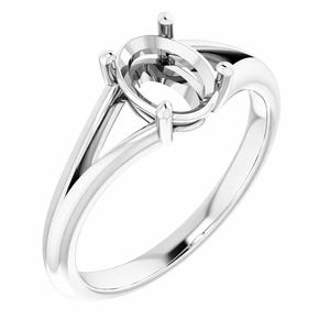 May include: A polished, silver-colored ring with an oval setting designed to hold a gemstone. The ring features a split shank design and prongs to secure the stone. The ring is shown against a white background.
