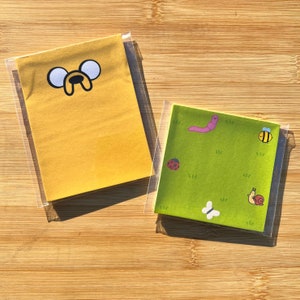 May include: Two sticky note pads, one yellow with a cartoon dog face and the other green with a worm, ladybug, snail, and bee.