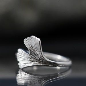 K&ouml;nnte beinhalten: Ein silberner Ring mit einem Ginkgoblatt-Design. Der Ring ist aus Sterlingsilber gefertigt und ein zartes und elegantes Schmuckst&uuml;ck.