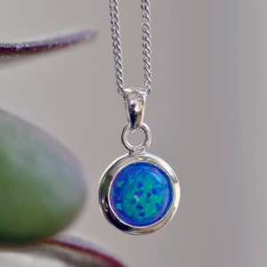 May include: A silver chain necklace with a round blue opal pendant.