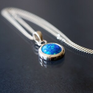 May include: A silver chain necklace with a pendant featuring a blue opal gemstone.