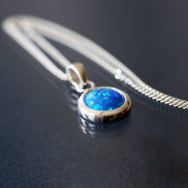 May include: A silver chain necklace with a pendant featuring a blue opal gemstone.