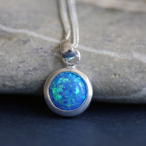 May include: A silver necklace with a round blue opal pendant.