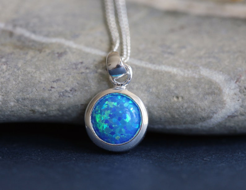 May include: A silver necklace with a round blue opal pendant.