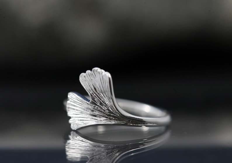 K&ouml;nnte beinhalten: Ein silberner Ring mit einem Ginkgoblatt-Design. Der Ring ist aus Sterlingsilber gefertigt und ein zartes und elegantes Schmuckst&uuml;ck.