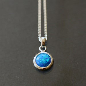 May include: A silver chain necklace with a round blue opal pendant.