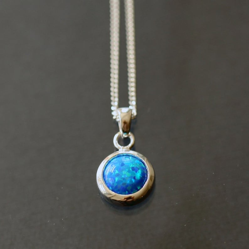 May include: A silver chain necklace with a round blue opal pendant.