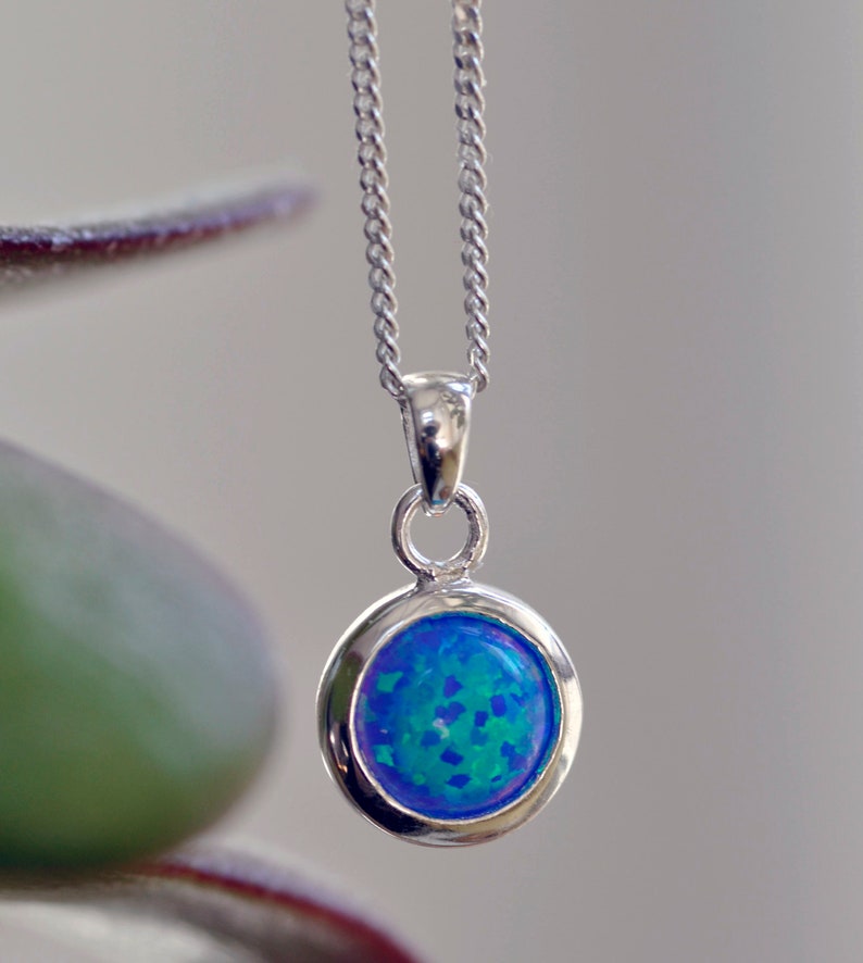 May include: A silver chain necklace with a round blue opal pendant.