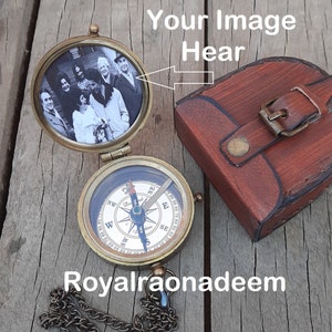 Könnte beinhalten: Kompass aus Messing mit einem Fotoeinsatz und einem Lederetui. Der Kompass hat eine Kette. Der Fotoeinsatz zeigt eine Gruppe von Menschen. Der Text "Your Image Hear" steht über dem Kompass.