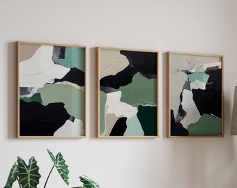 May include: Three framed abstract art prints with a modern design. The artwork features a palette of black, white, and various shades of green. The frames are a light wood color, and the art is displayed on a white wall.