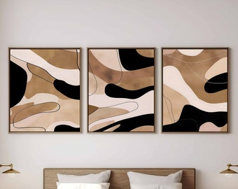 Könnte beinhalten: Drei abstrakte Kunstdrucke in Braun-, Beige- und Schwarztönen. Die Drucke sind in einem dünnen, hellbraunen Rahmen gerahmt und an einer weißen Wand über einem Holzbettgestell aufgehängt.