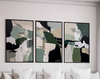 May include: Three abstract art prints in black frames with green, black, and white geometric shapes. The prints are hanging on a white wall above a white couch with pillows.