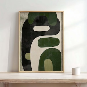 May include: Abstract art print in a wooden frame. The artwork features organic shapes in shades of green, black, and off-white. The framed art is displayed on a light-coloured wooden surface. A white mug sits on the table.