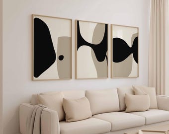 Könnte beinhalten: Drei gerahmte abstrakte Kunstdrucke mit schwarzen, beigen und braunen Formen. Das Kunstwerk hängt über einem cremefarbenen Sofa mit passenden Kissen. Ein Holztisch und ein neutraler Vorhang sind ebenfalls zu sehen.