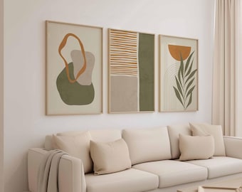 May include: Three framed abstract art prints with neutral colors. The artwork features geometric shapes, lines, and organic forms in shades of olive green, beige, and burnt orange. The prints are displayed above a cream-colored sofa.