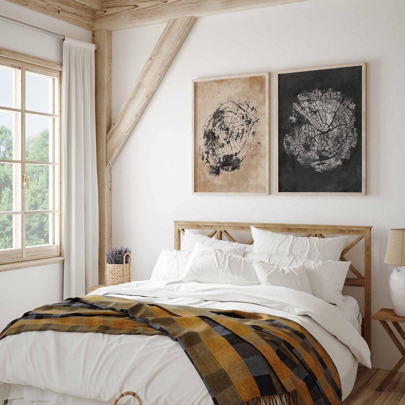 May include: A white bed with a yellow and black plaid throw blanket. The bed has a wooden headboard and is against a white wall. There are two black and white framed prints of tree rings on the wall above the bed.