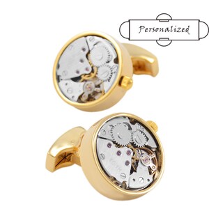 Puede incluir: Un par de gemelos de oro con una cara redonda y transparente que revela un mecanismo de reloj en funcionamiento. Los gemelos son un accesorio único y elegante para cualquier ocasión.