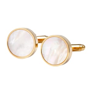 May include: A pair of gold-toned cufflinks with a round, mother-of-pearl face. The cufflinks have a polished finish and a classic design, suitable for formal wear. The mother-of-pearl has a subtle, iridescent sheen.