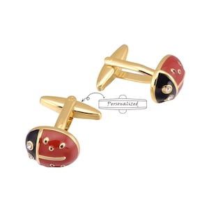 May include: Gold-tone cufflinks with a red and black enamel ladybug design. The ladybug has black spots and a single rhinestone.