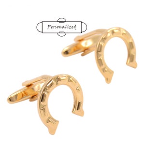 以下が含まれることがあります： 金色の馬蹄形の袖口用ボタンのペア。袖口用ボタンは、テクスチャ加工された馬蹄形のデザインで装飾されています。